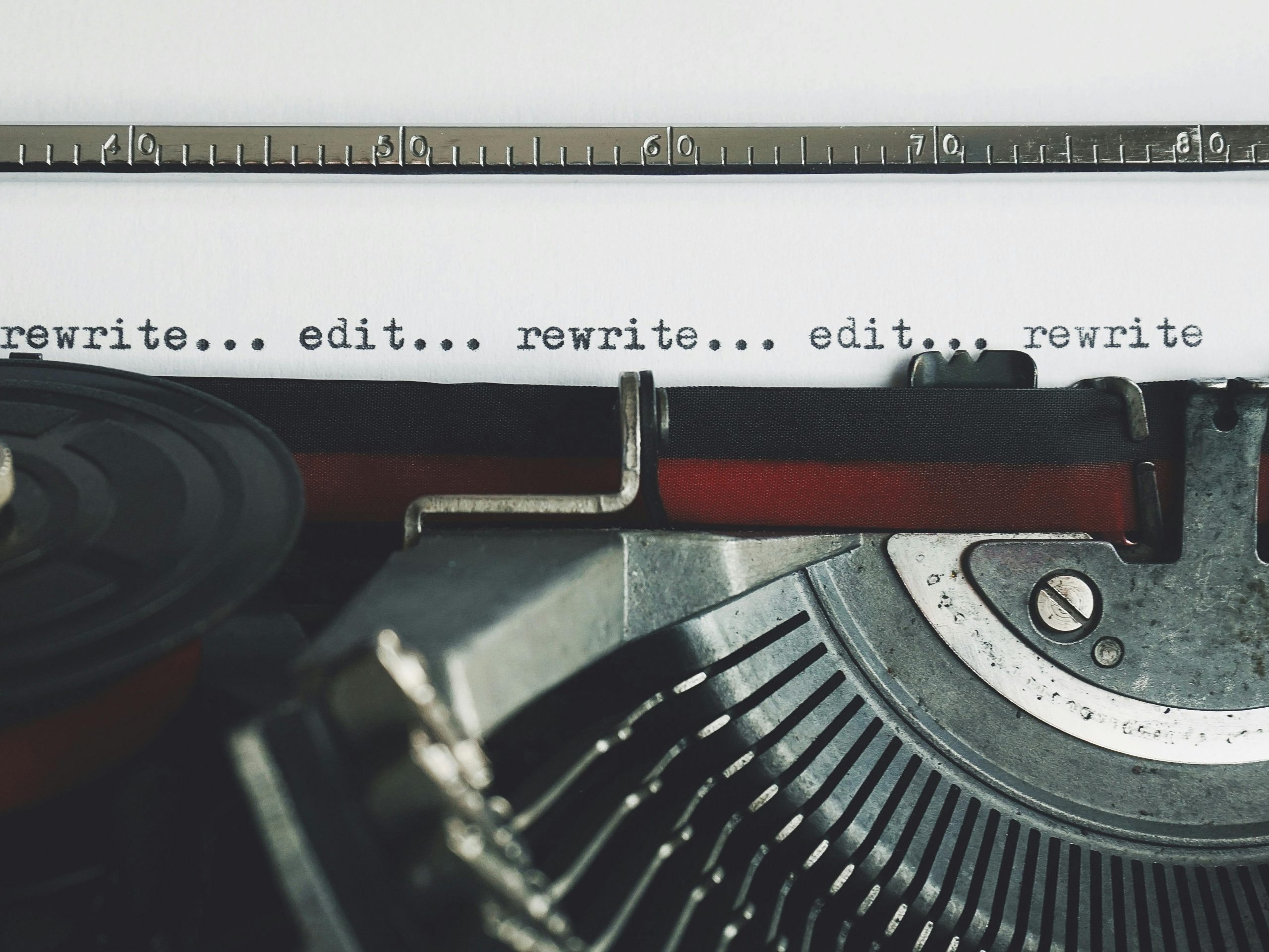 Type writer with a piece of paper inside that has the words:rewrite...edit..rewrite...edit..rewritetyped on the page